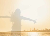 Silhouette of a girl stretching arms in front of city.