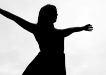 Silhouette of young woman, arms out.