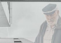 Older man reflecting outside of a building.