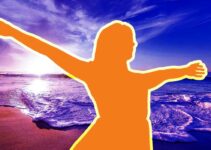 Silhouette of girl with outstretched arms before ocean.
